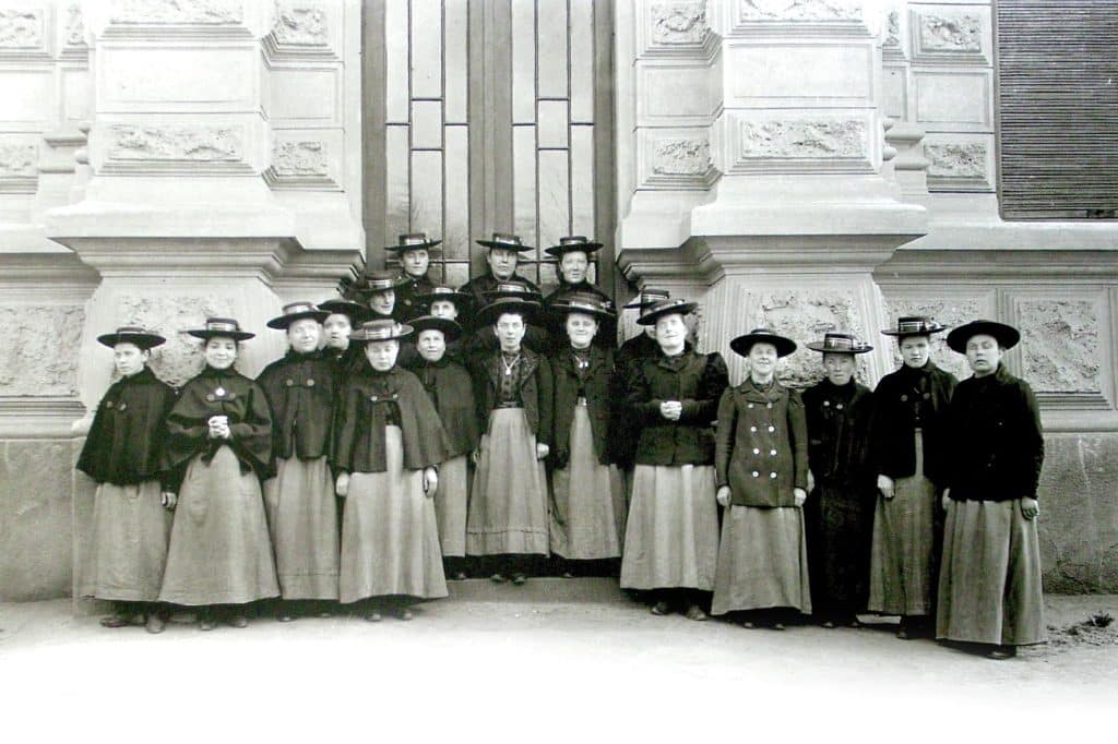 Eine Gruppe von Frauen und Mädchen in einer alten Tracht vor einem historischen Gebäude.