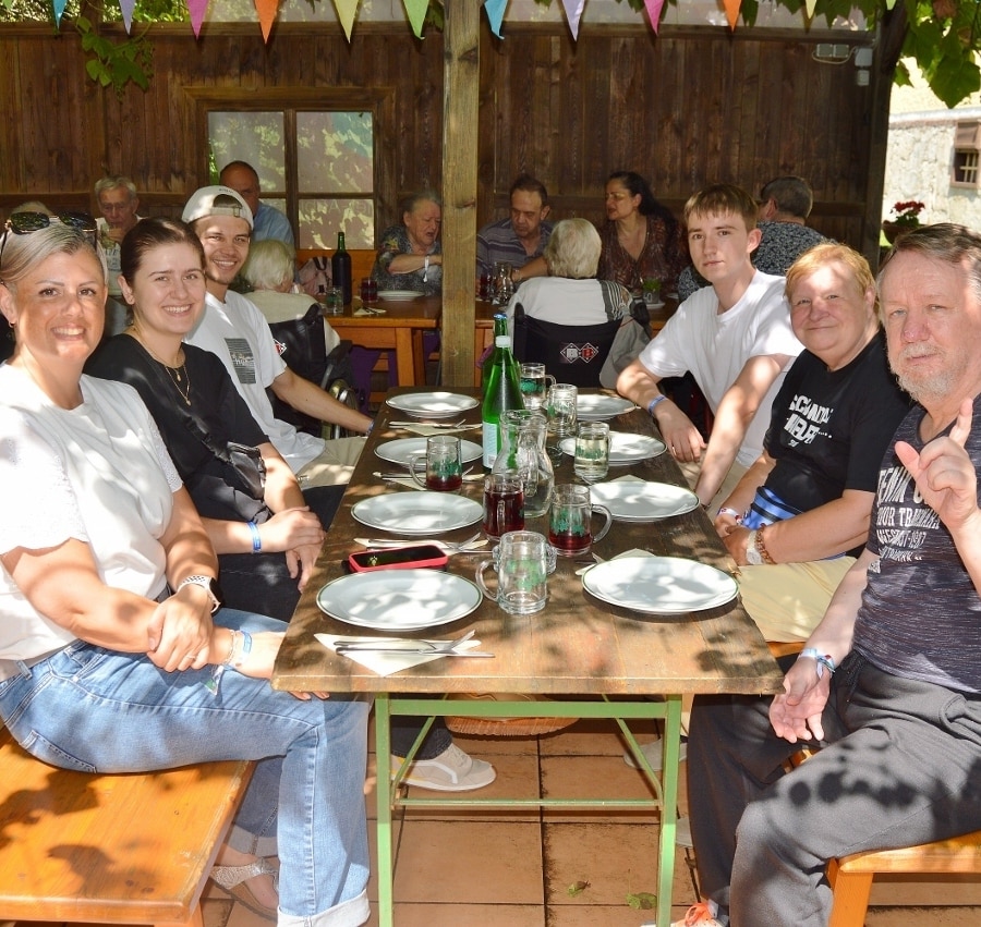 Gruppe von Senior:innen und Begleiter:innen an einem Tisch sitzend in der Buschenschank.